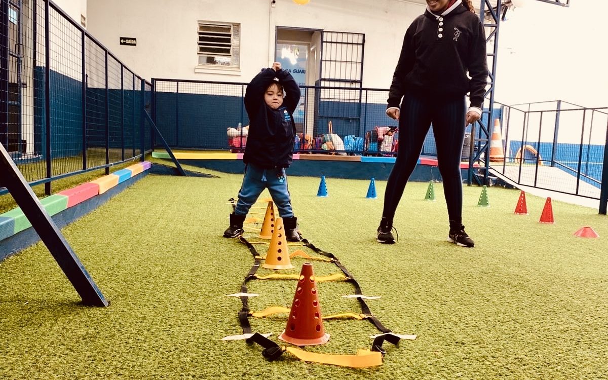 Professora acompanhando criança no circuito psicomotor